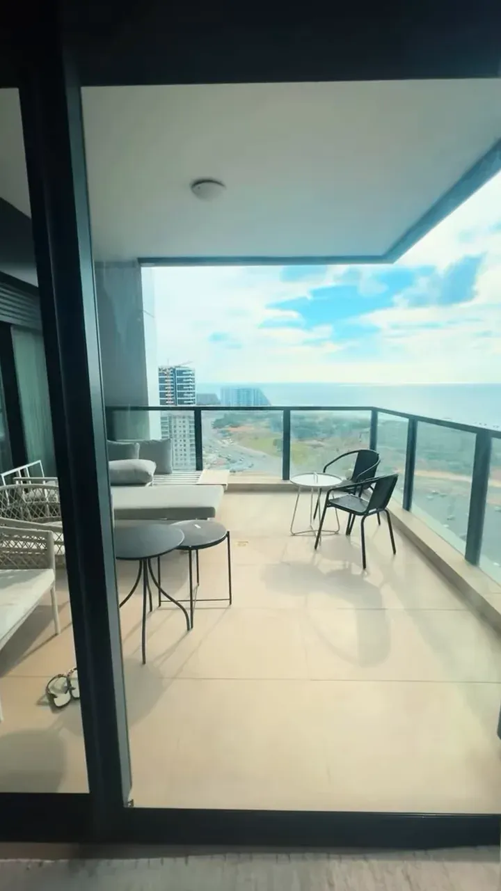 Varanda com cadeiras e mesa pequena de frente para o mar