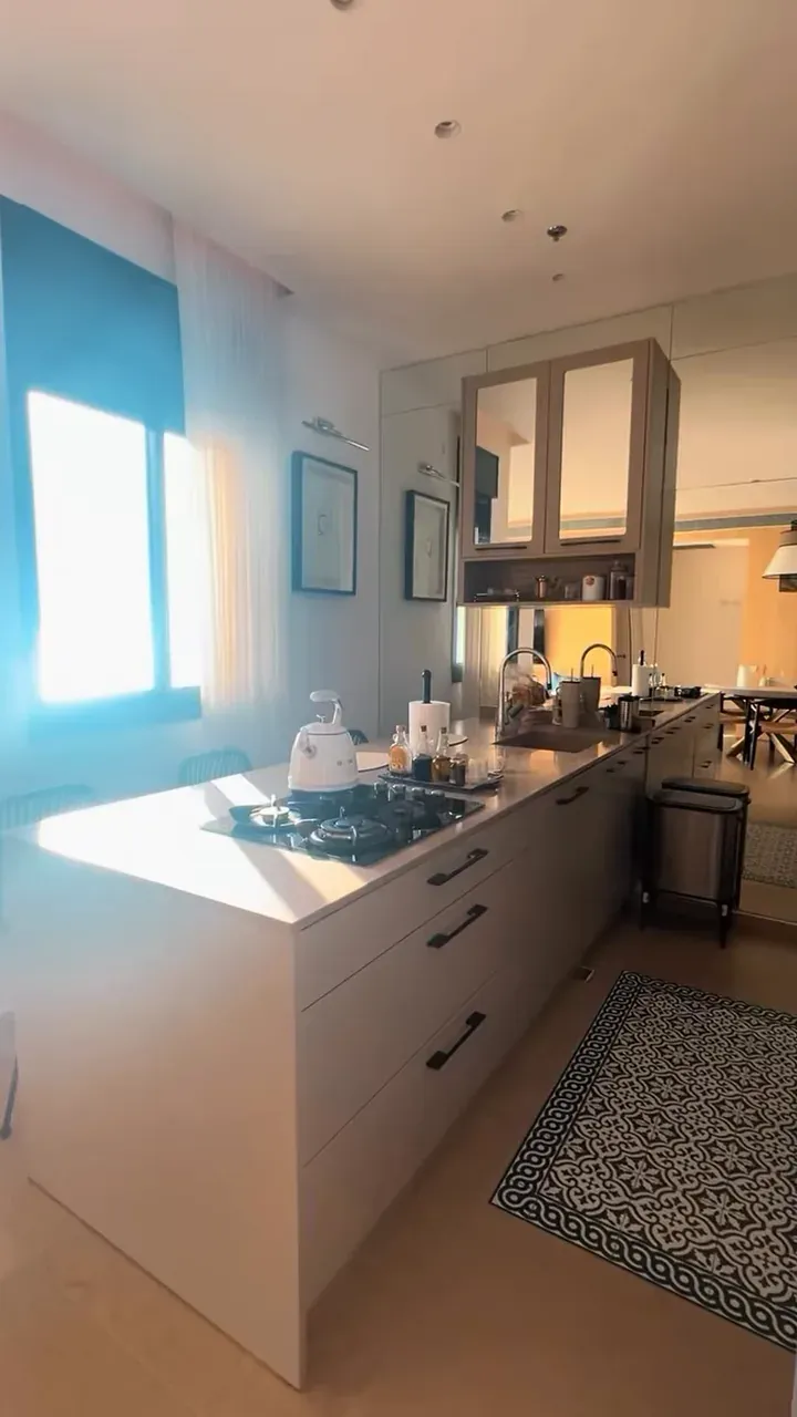Cozinha com bancada limpa, cooktop e tapete no chão